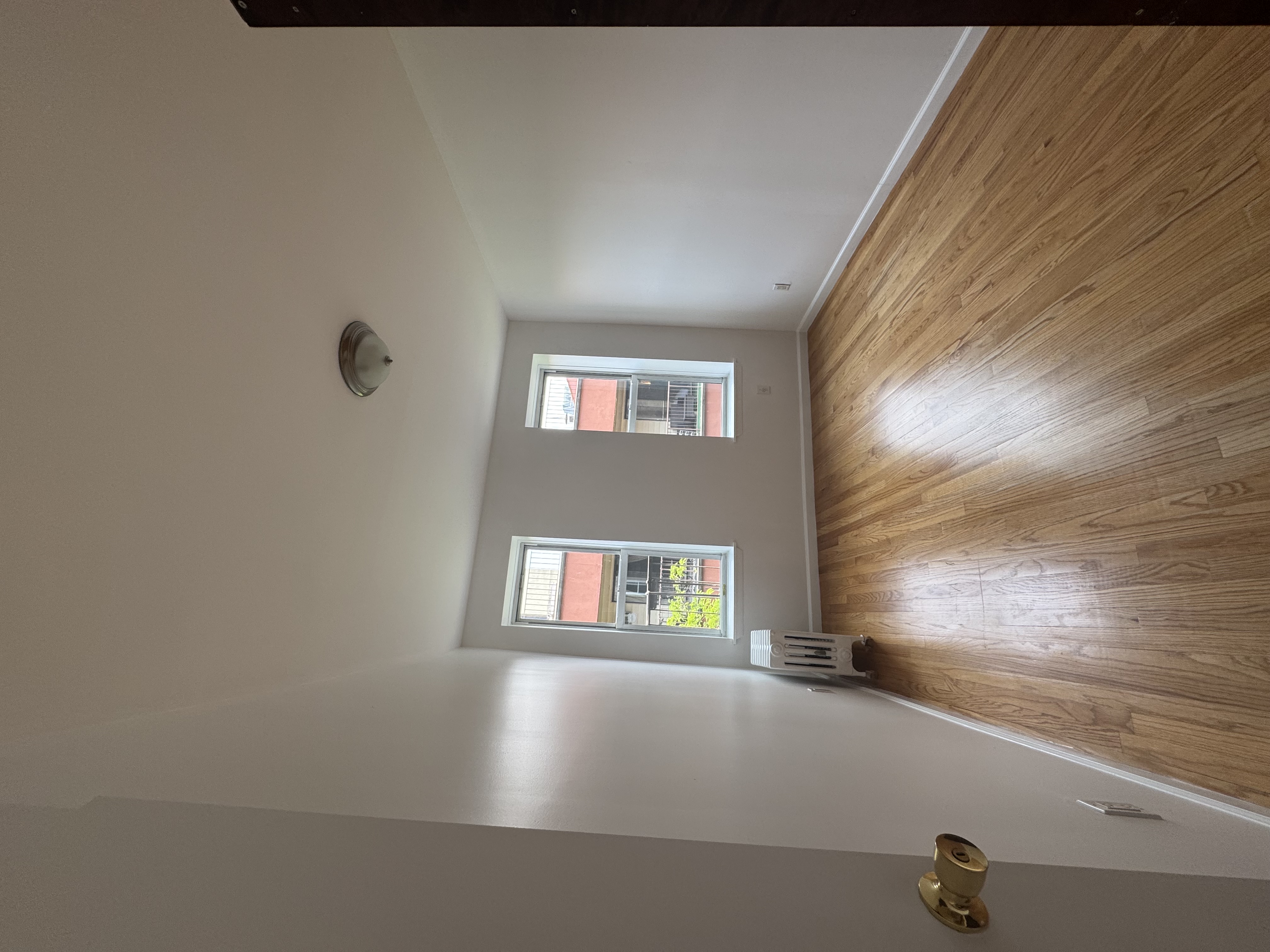 451 West 44th Street, Unit 63 Manhattan, NY 10036 - Photo 4 of 31 an empty room with wooden floor and windows