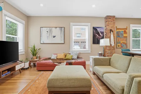 a living room with furniture wooden floor and kitchen view