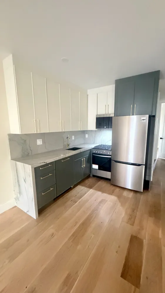 a kitchen with stainless steel appliances granite countertop a refrigerator a sink a stove and white cabinets