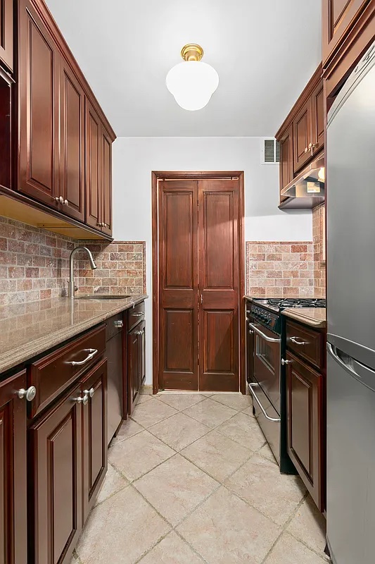 4 West 109th Street, Unit 4F Manhattan, NY 10025 - Photo 4 of 16 a kitchen with granite countertop wooden cabinets and stainless steel appliances