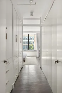 a hallway with white doors wooden floor and front door