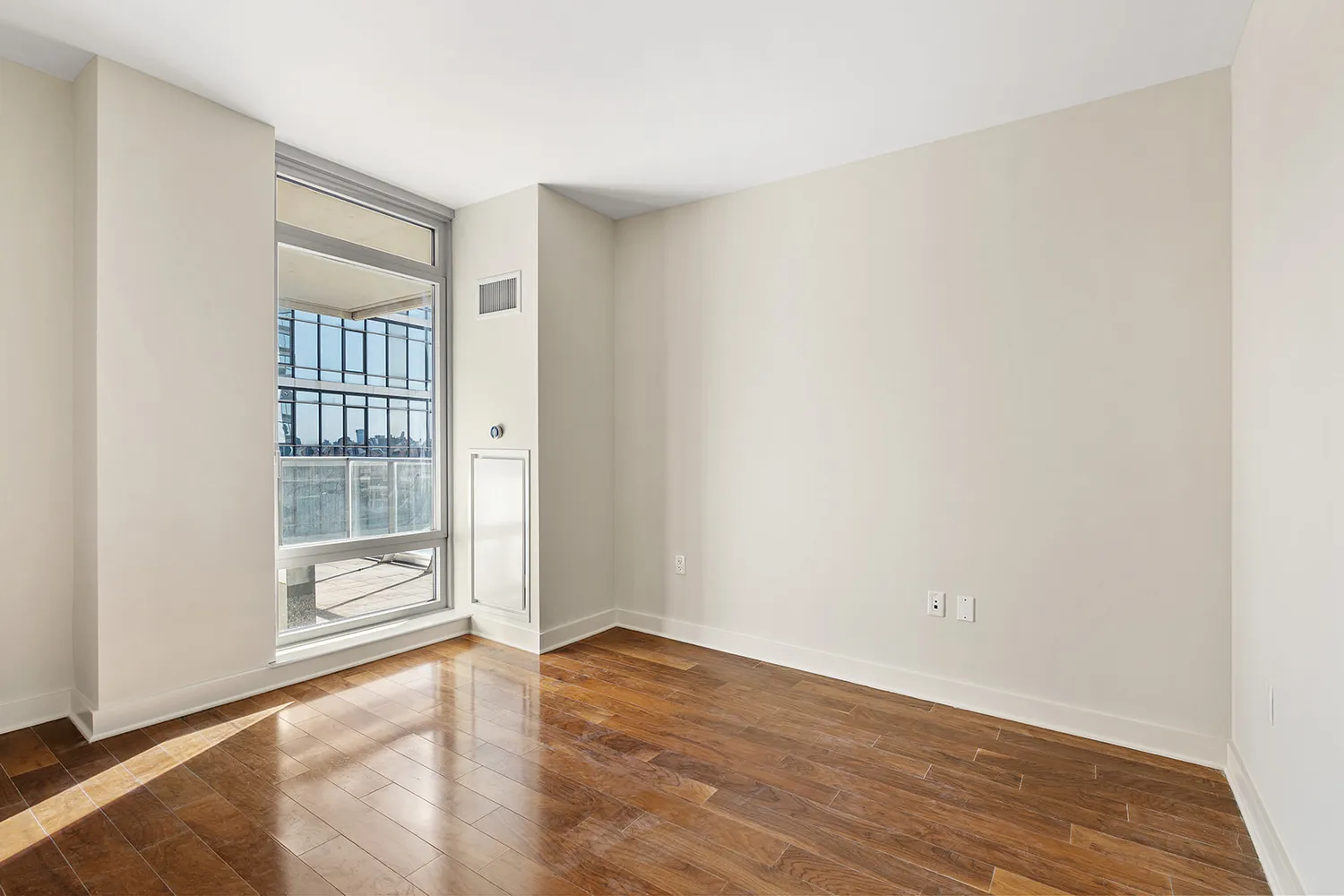 an empty room with wooden floor and windows