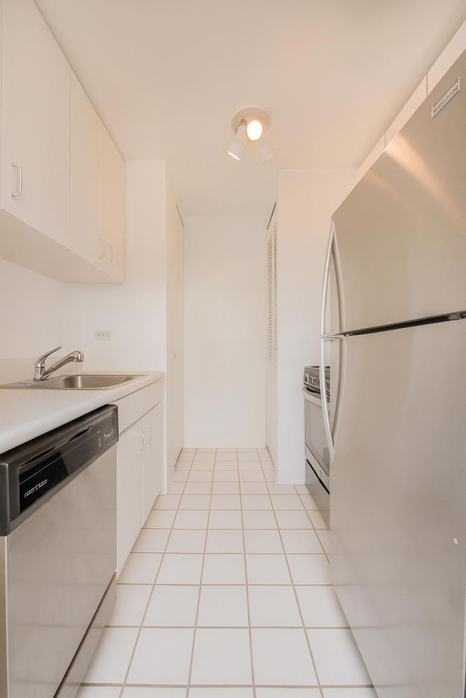 161 West 61st Street, Unit 19D Manhattan, NY 10023 - Photo 3 of 12 a kitchen with white cabinets and white appliances