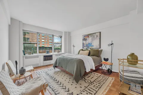 a spacious bedroom with a bed a couch and large window