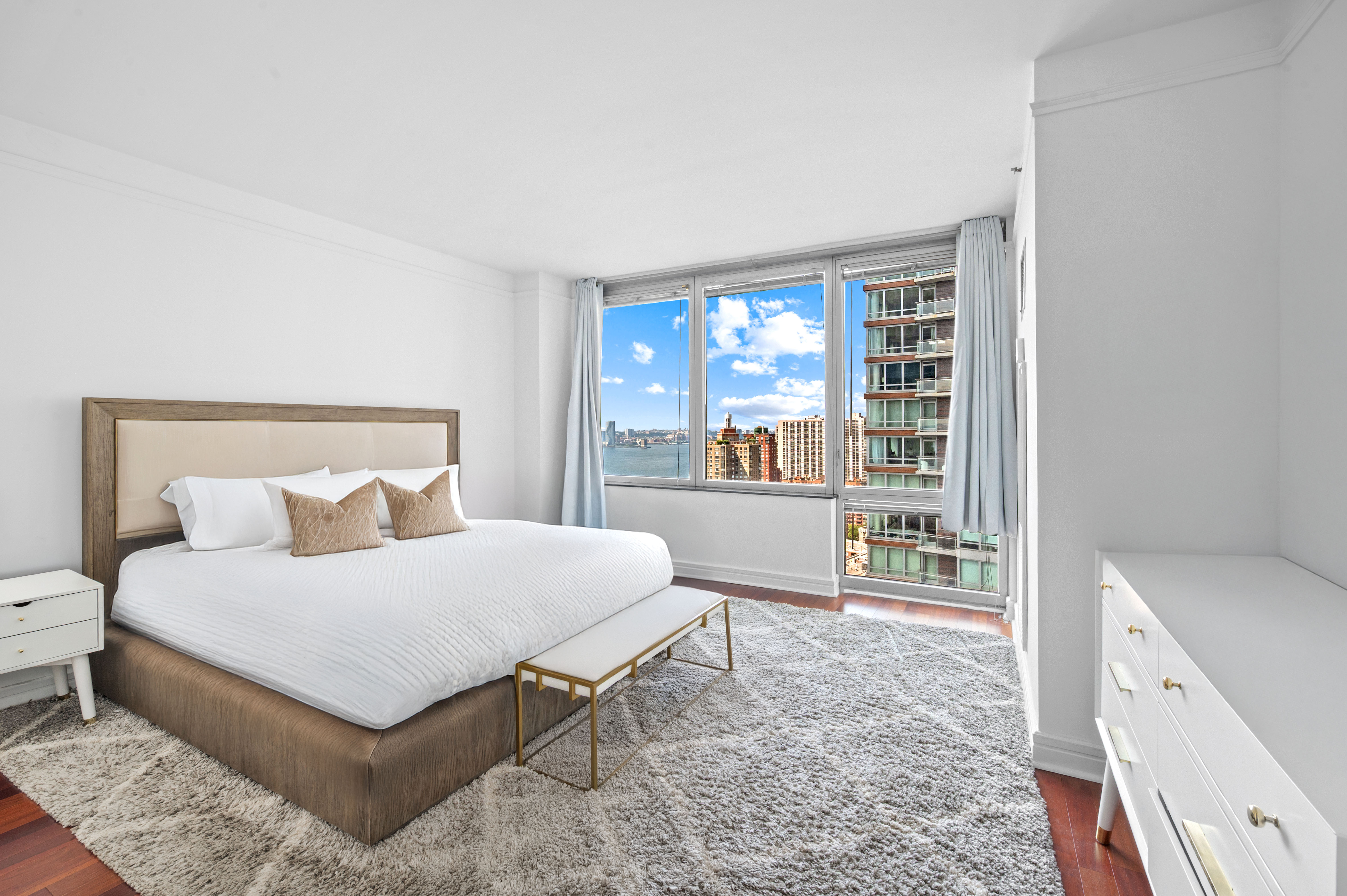 10 West Street, Unit 28C Manhattan, NY 10004 - Photo 6 of 12 a bedroom with a bed a table and three large window