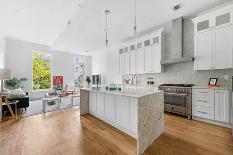 a kitchen with stainless steel appliances white cabinets a sink a stove a refrigerator and a window