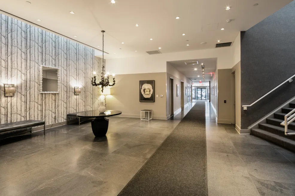 a living room with stainless steel appliances furniture a rug and a kitchen