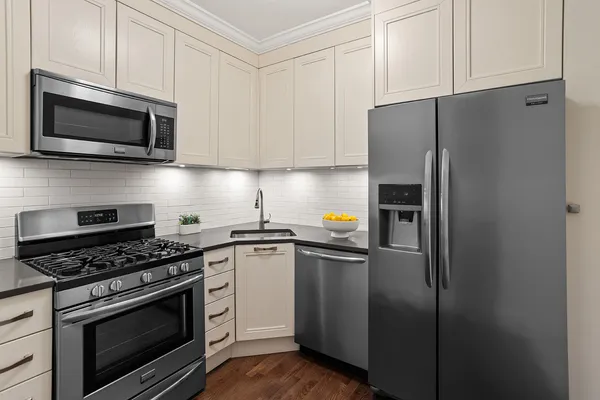 a kitchen with cabinets stainless steel appliances and a wooden floor