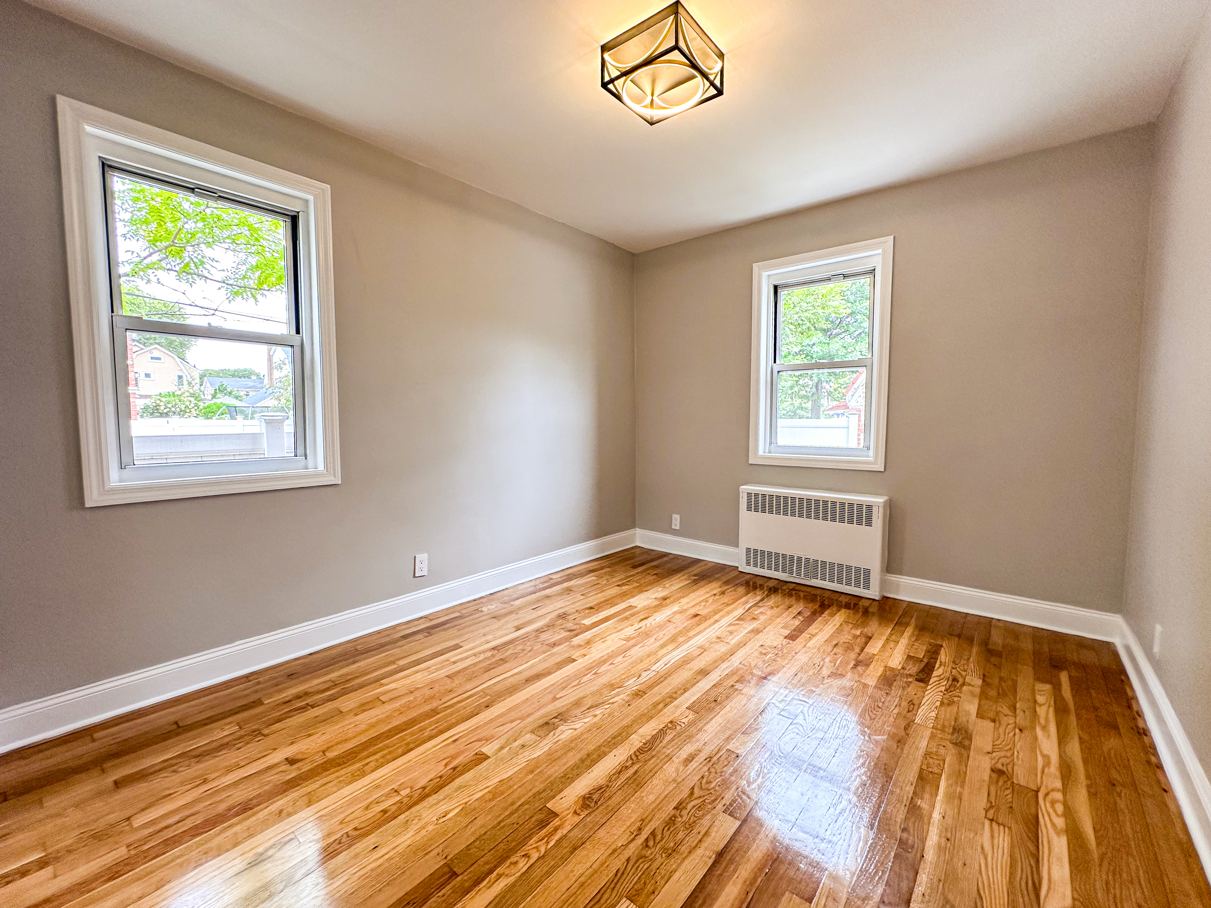 10-01 154th Street, Unit 1 Queens, NY 11357 - Photo 7 of 10 a view of an empty room with wooden floor and a window