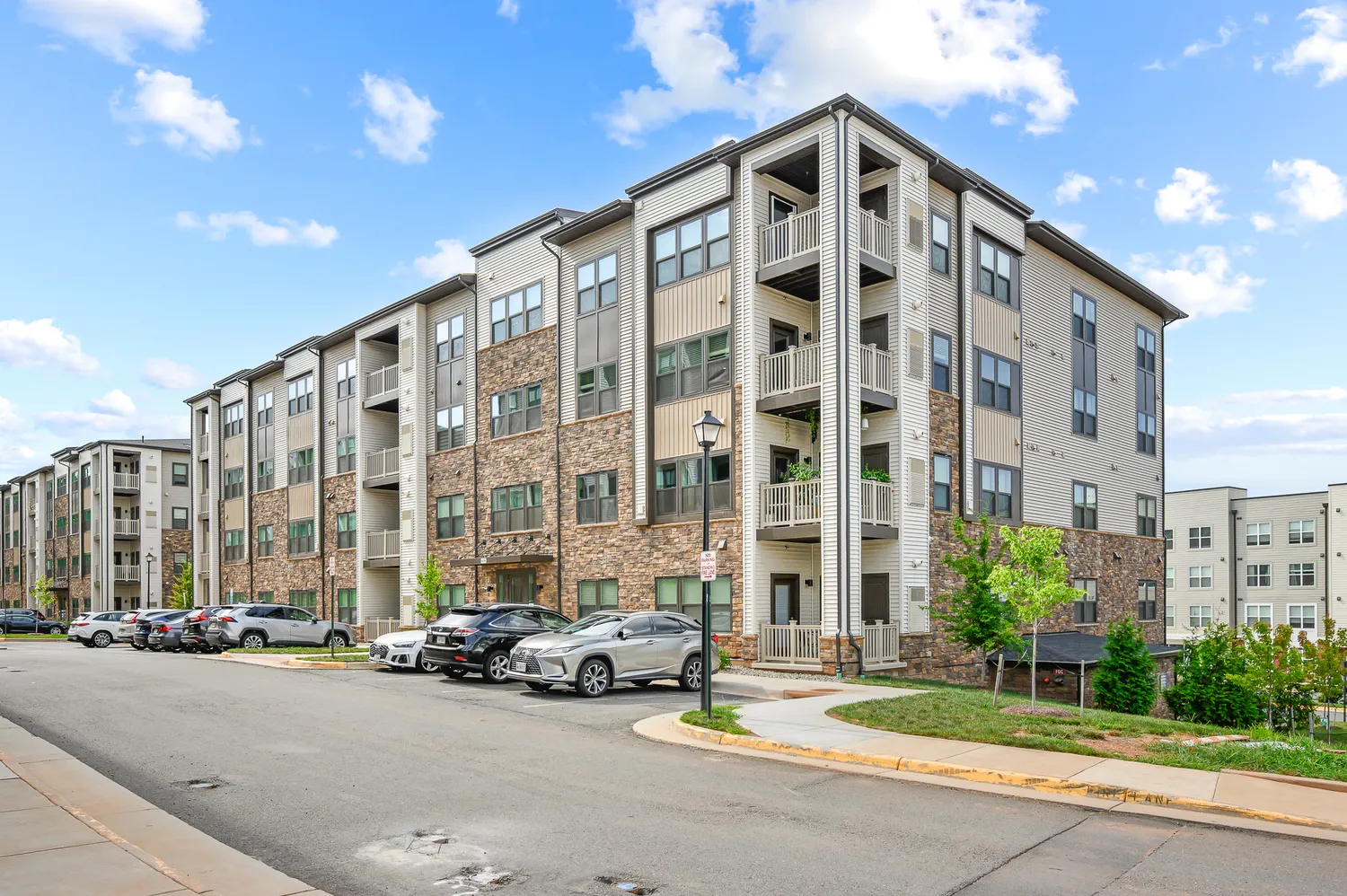 front view of a brick building with a car parked beside a road