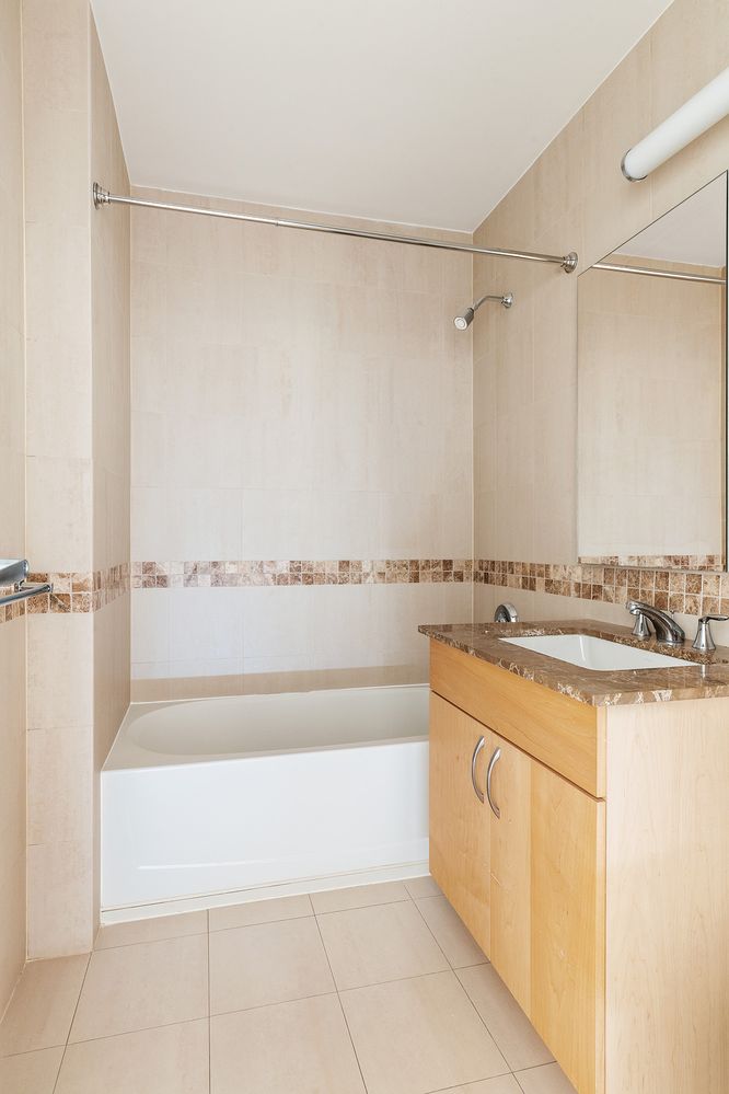 40 West 116th Street, Unit A808 Manhattan, NY 10026 - Photo 7 of 19 a bathroom with a granite countertop sink and a bathtub