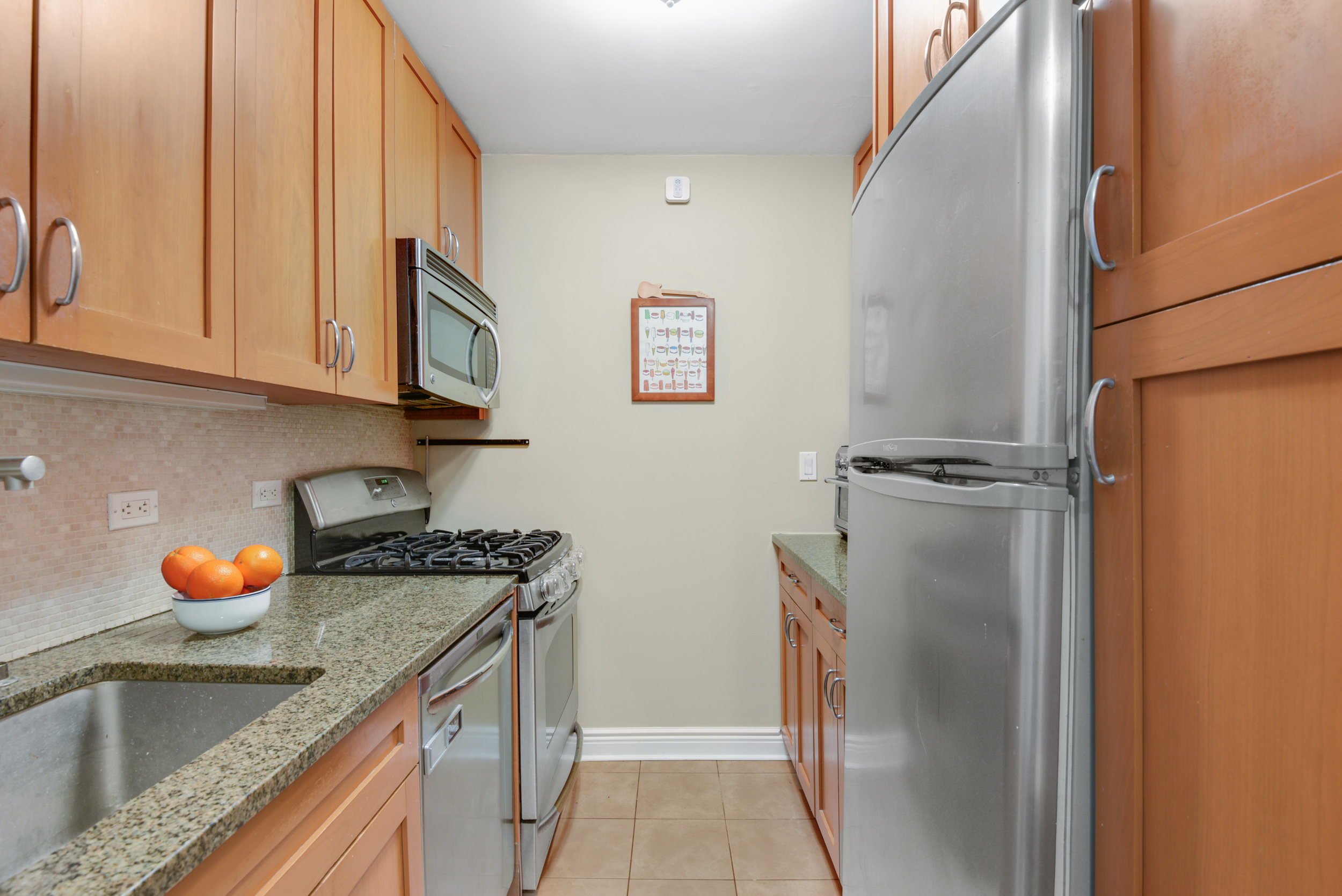 345 East 73rd Street, Unit 7J Manhattan, NY 10021 - Photo 6 of 13 a kitchen with a sink a refrigerator and cabinets