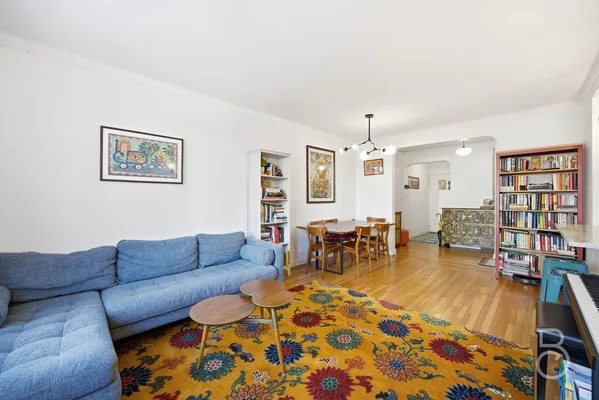 a living room with furniture and a dining table with bookshelf