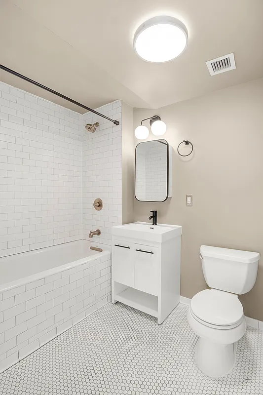 293 Hawthorne Street, Unit 2E Brooklyn, NY 11225 - Photo 6 of 21 a bathroom with a toilet a sink a mirror and a bathtub