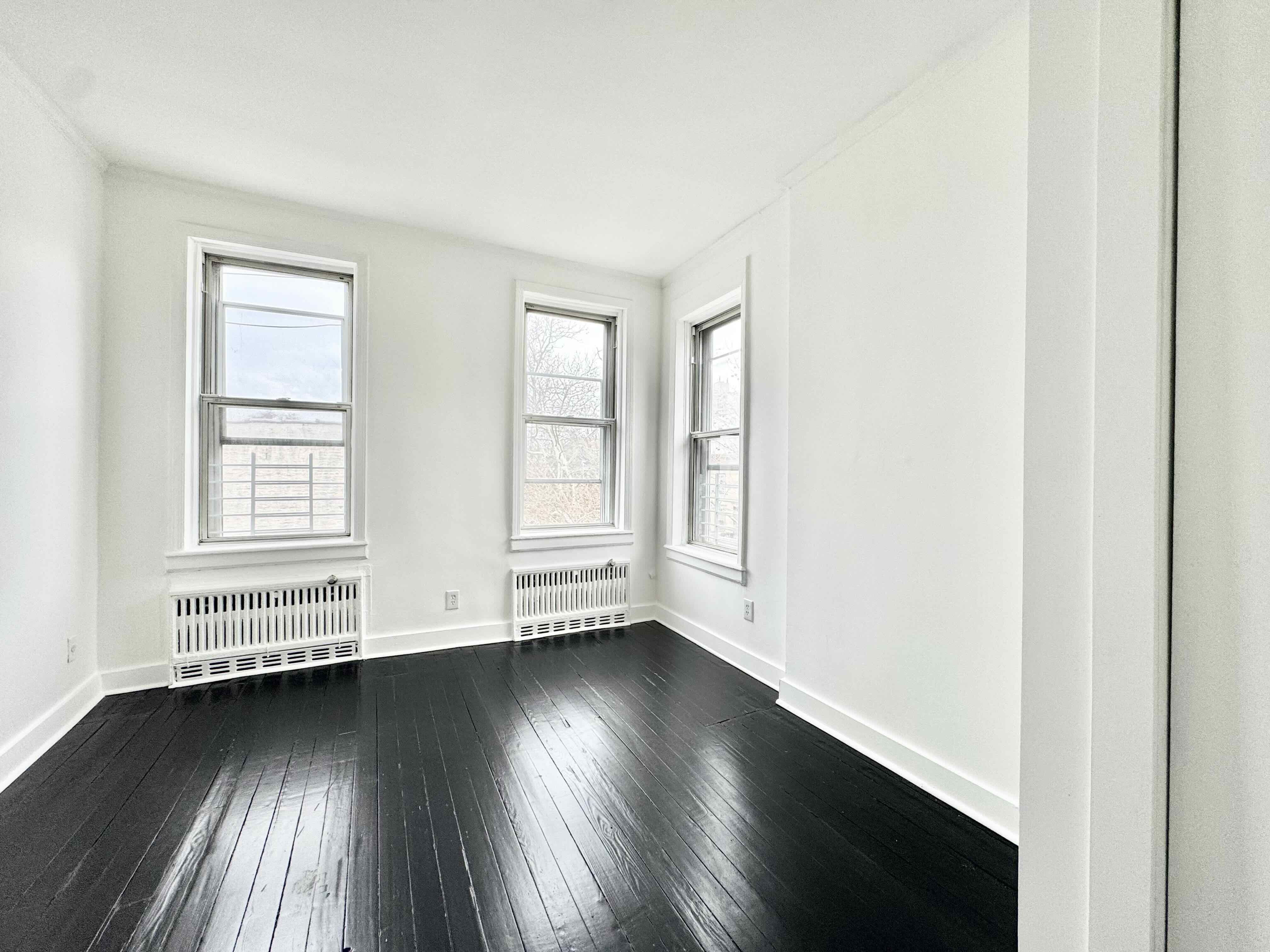 406 Rogers Avenue, Unit 3 Brooklyn, NY 11225 - Photo 7 of 9 an empty room with wooden floor and windows