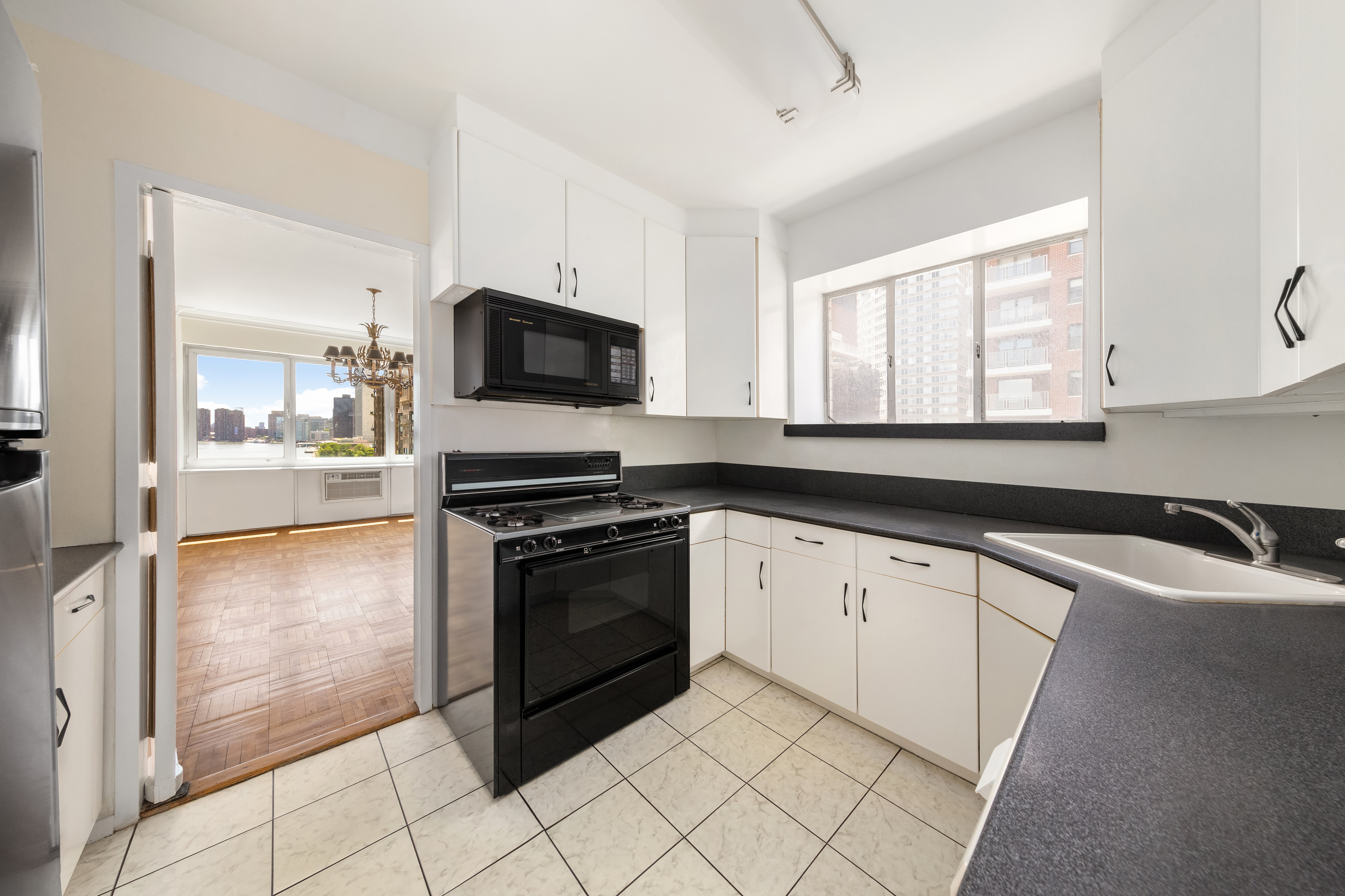 45 Sutton Place South, Unit 14N Manhattan, NY 10022 - Photo 7 of 19 a kitchen with stainless steel appliances granite countertop a stove a sink and a microwave