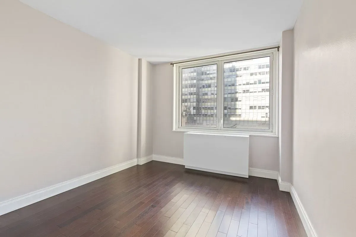 212 East 47th Street, Unit 21D Manhattan, NY 10017 - Photo 3 of 16 an empty room with wooden floor and windows