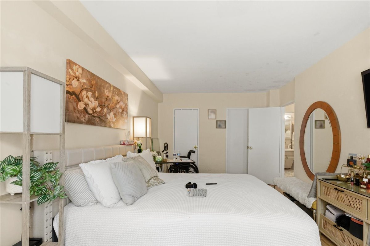 448 Neptune Avenue, Unit 14J Brooklyn, NY 11224 - Photo 11 of 21 a bedroom with a bed a mirror and a potted plant