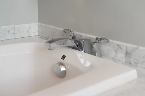 a bedroom with a bed and a lamp on dresser