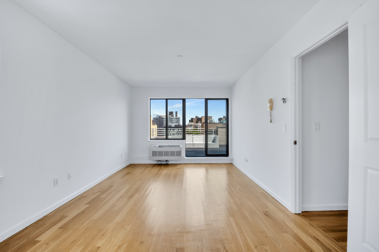 416 East 117th Street, Unit PH6 Manhattan, NY 10035 - Photo 9 of 18 a view of an empty room with wooden floor and a window