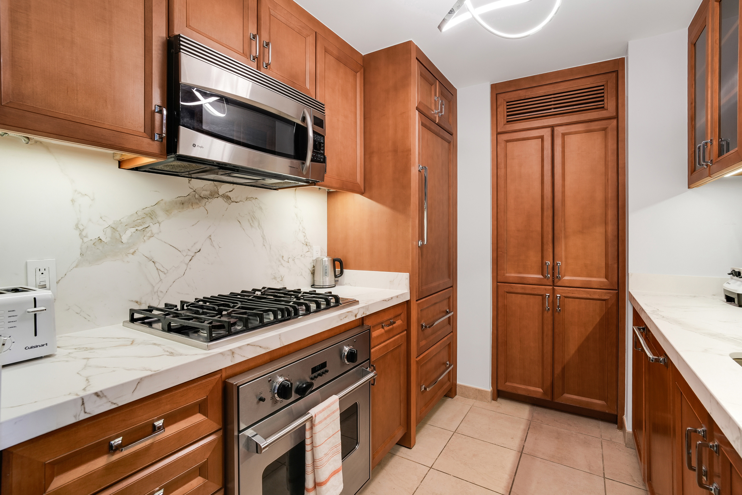 205 East 85th Street, Unit 16H Manhattan, NY 10028 - Photo 4 of 14 a kitchen with stainless steel appliances a stove a microwave and a sink