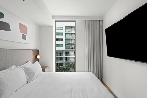 a bed room with a bed tv and a window
