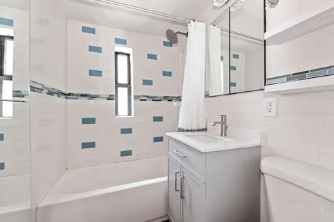 a bathroom with a granite countertop sink a toilet a mirror a bathtub and shower