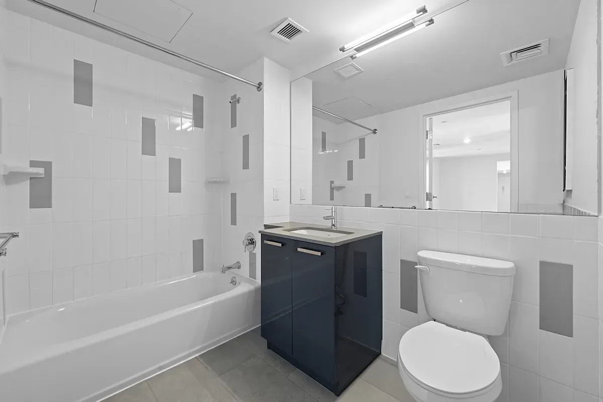 a bathroom with a toilet a sink a mirror a bathtub and vanity