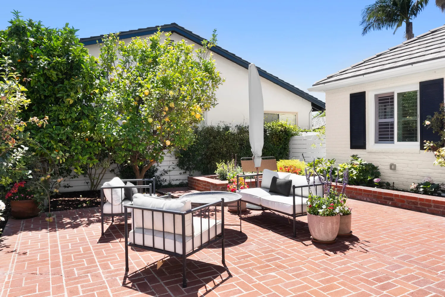 a view of a patio with couches table and chairs and potted plants