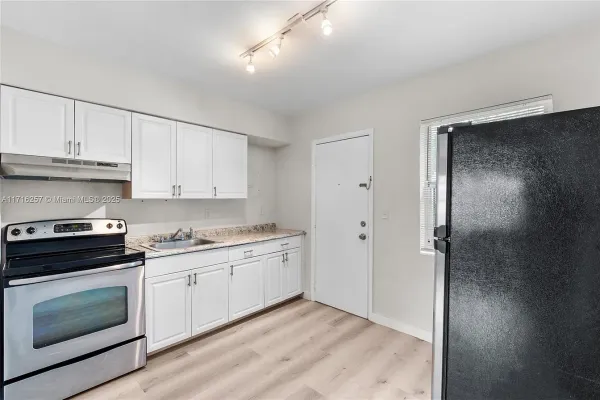 a kitchen with granite countertop white cabinets and stainless steel appliances