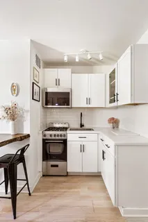a kitchen with stainless steel appliances granite countertop a stove top oven a sink dishwasher and white cabinets