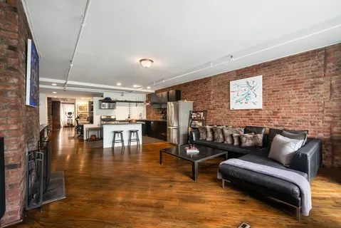 a living room with couches and kitchen view with wooden floor