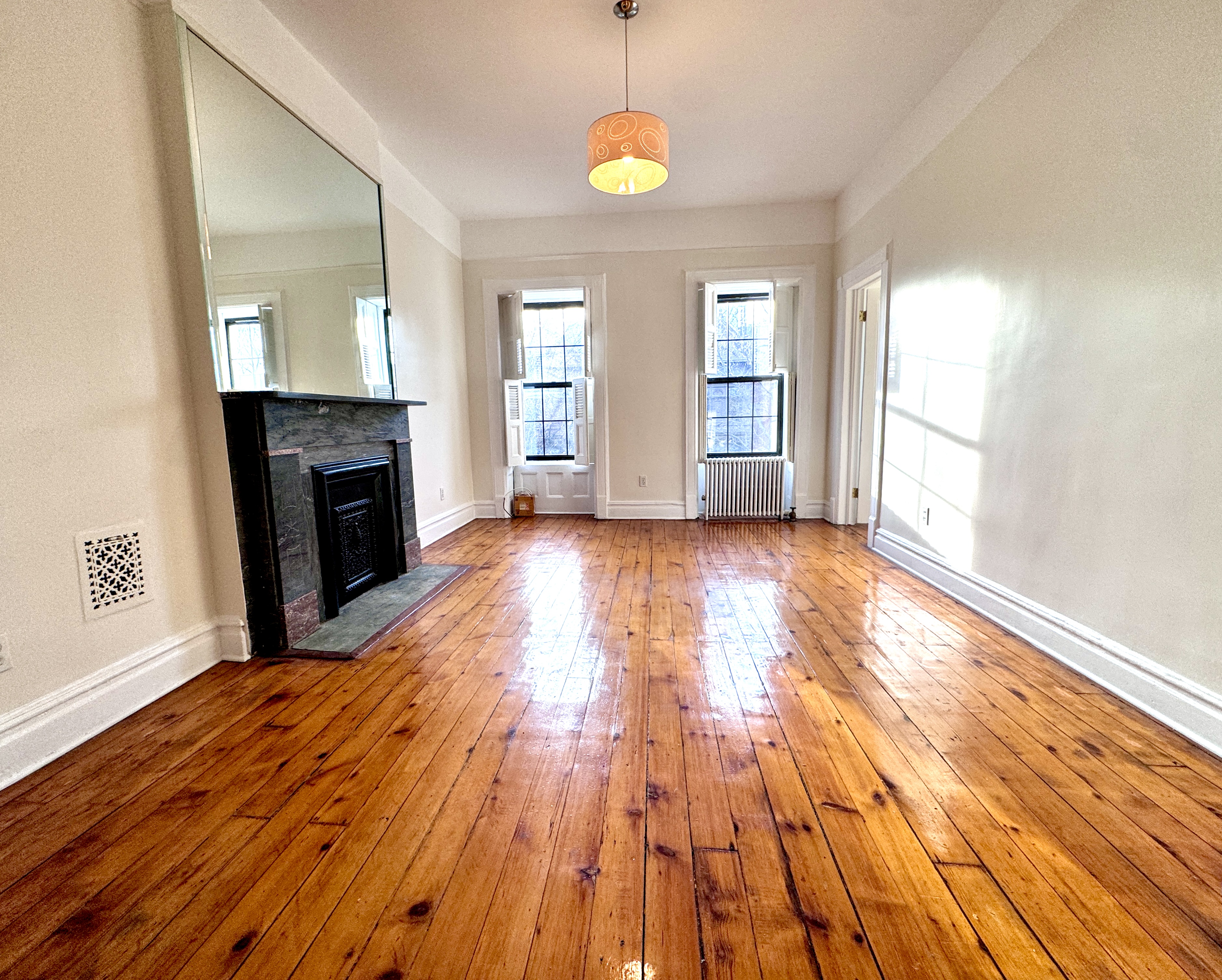 an empty room with wooden floor fireplace and windows