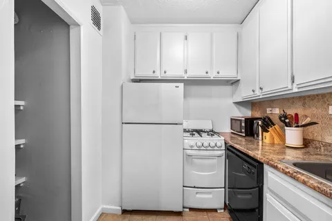 a kitchen with granite countertop white cabinets and white appliances