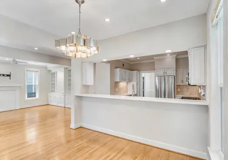 a view of a big room with wooden floor and a kitchen