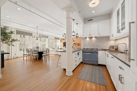 a kitchen with granite countertop lots of white cabinets stainless steel appliances and dining table