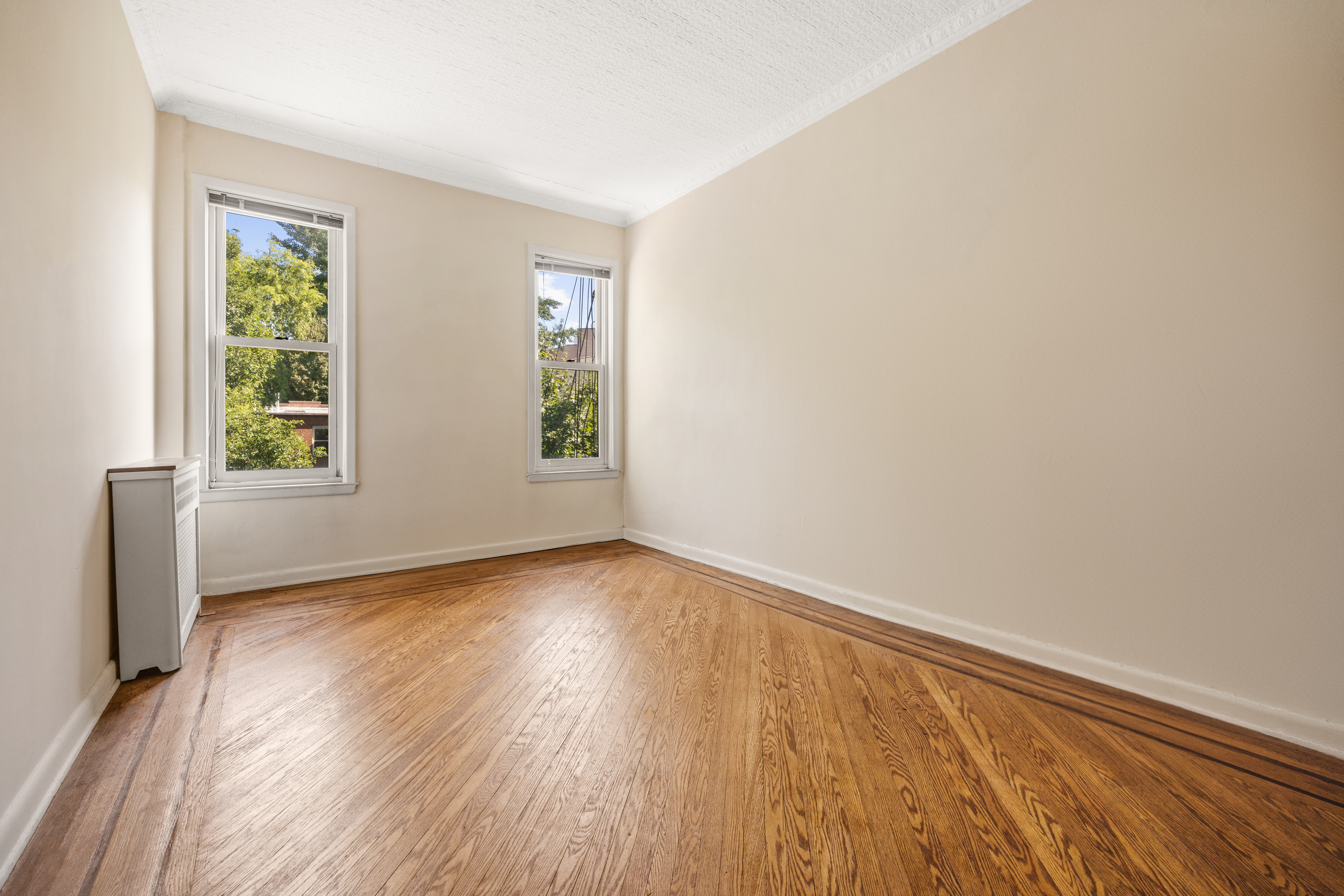 273 Windsor Place Brooklyn, NY 11218 - Photo 21 of 29 an empty room with wooden floor and windows