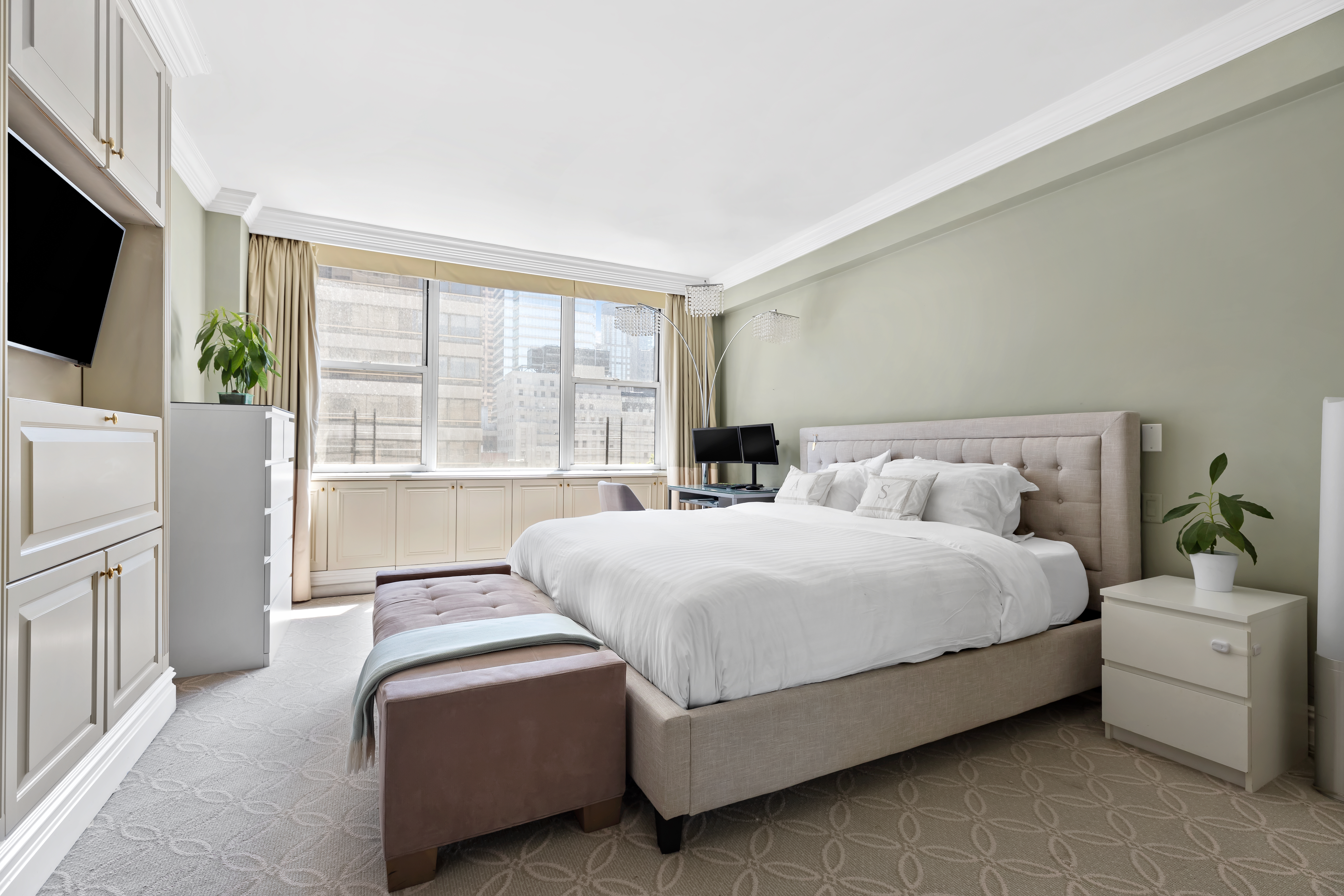 175 East 62nd Street, Unit 9D Manhattan, NY 10065 - Photo 6 of 12 a bedroom with bed a flat tv screen and a large window with the outer view