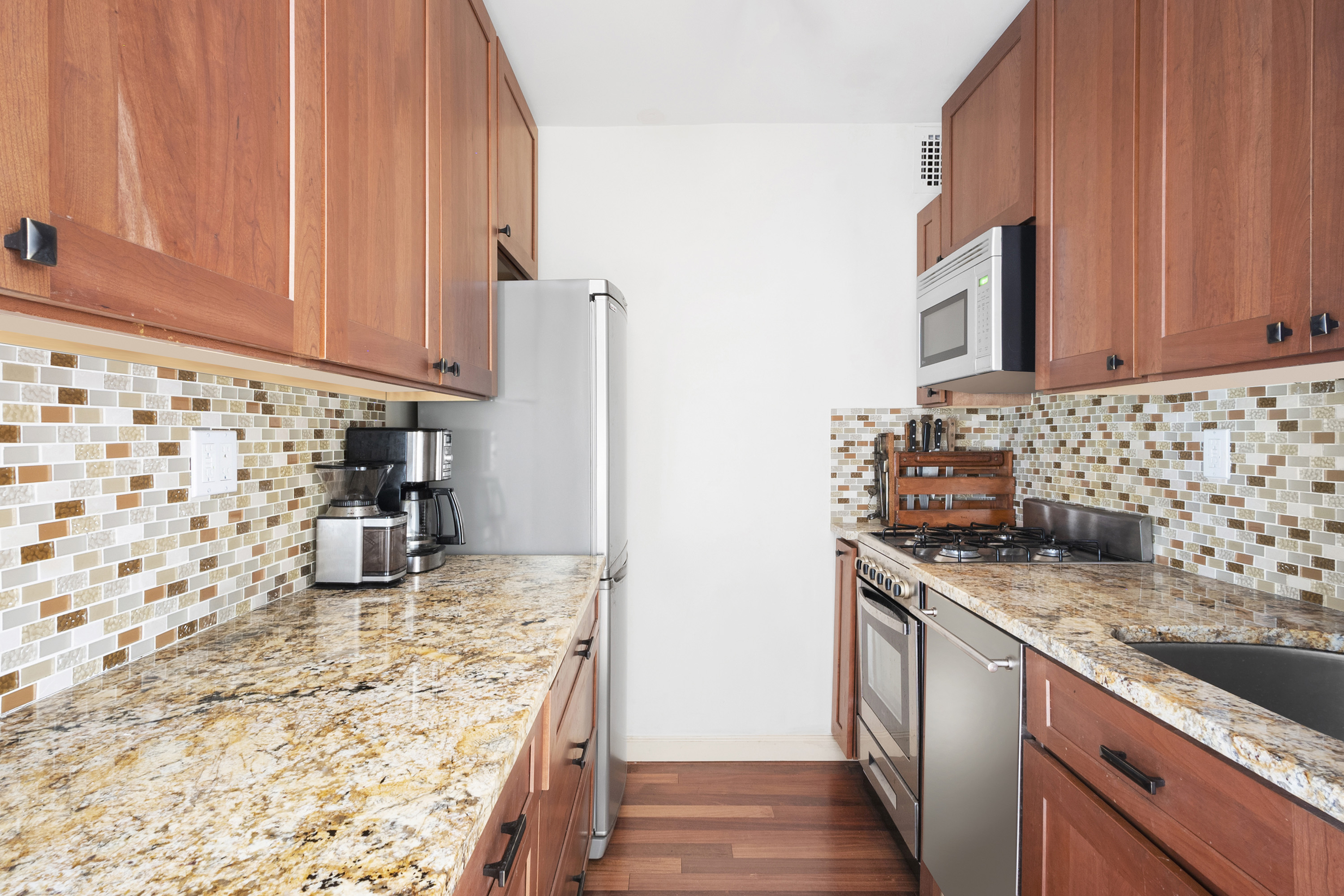 180 West End Avenue, Unit 28S Manhattan, NY 10023 - Photo 6 of 10 a kitchen with kitchen island granite countertop a sink stove and cabinets