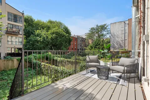 a balcony with wooden floor table and chairs