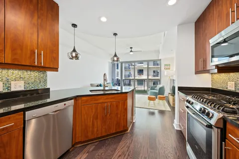 a kitchen with stainless steel appliances granite countertop a stove top oven a sink dishwasher and cabinets with wooden floor