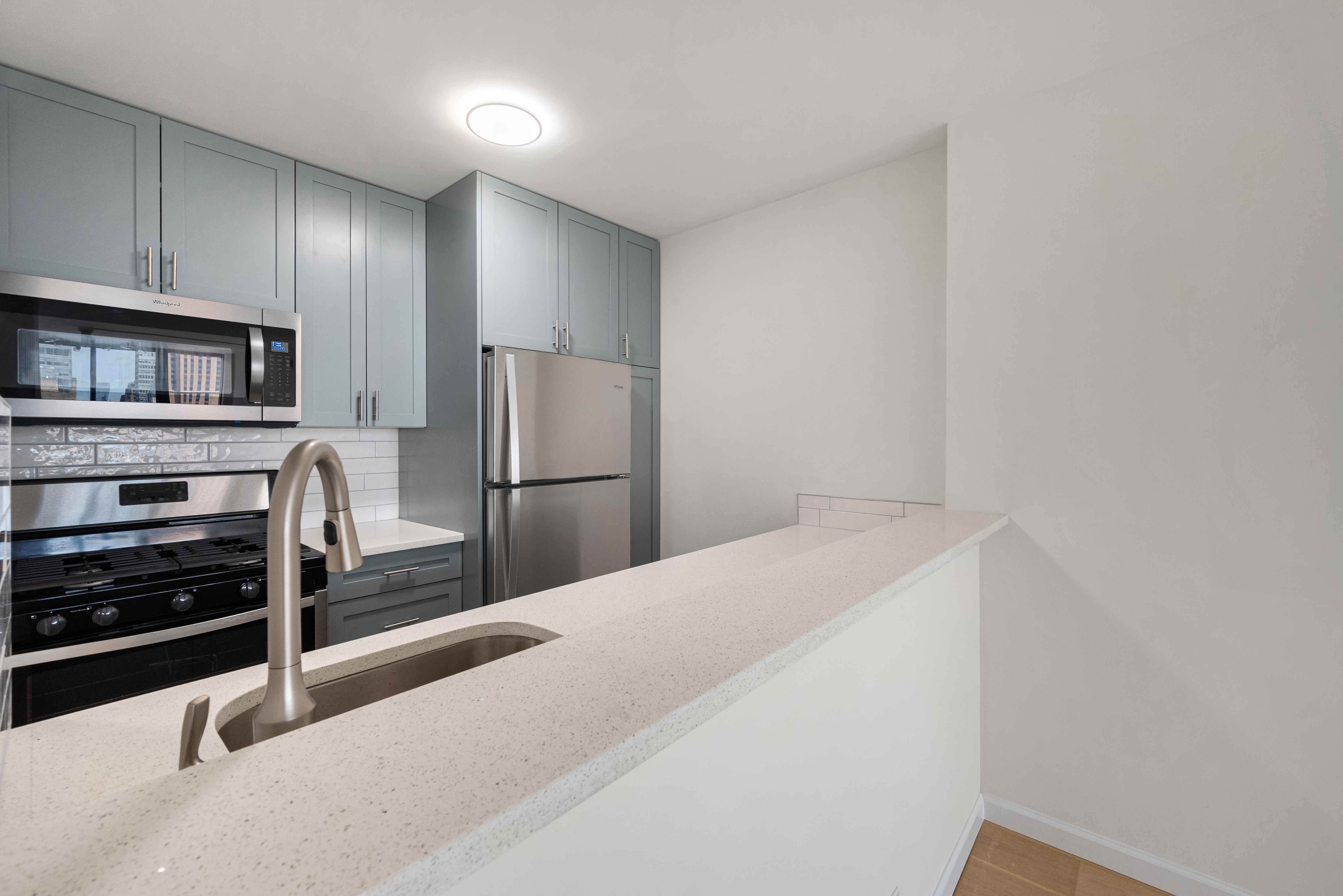 445 5th Avenue, Unit 26C Manhattan, NY 10016 - Photo 4 of 11 a kitchen with granite countertop a refrigerator and a stove top oven