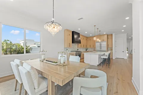 a dining room filled chandelier and kitchen view