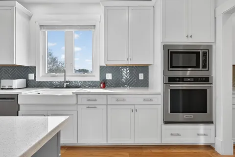 a kitchen with granite countertop white cabinets stainless steel appliances and a sink
