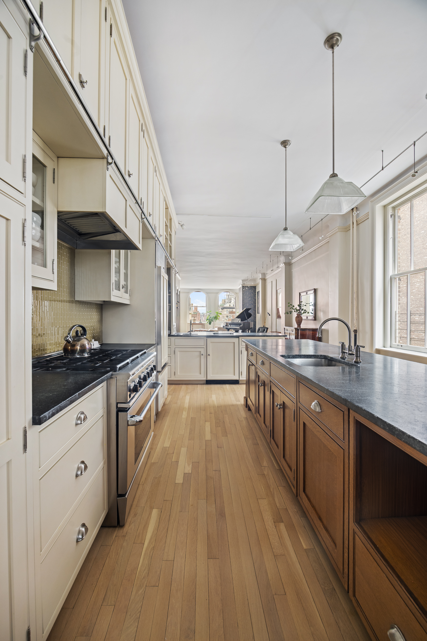 714 Broadway, Unit 8 Manhattan, NY 10003 - Photo 20 of 23 a kitchen with stainless steel appliances granite countertop wooden floors and view of living room