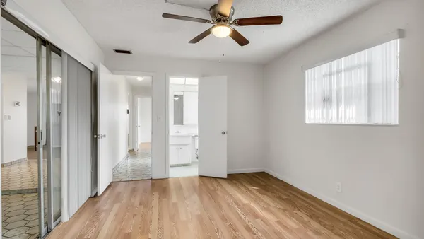 a view of empty room with wooden floor and fan