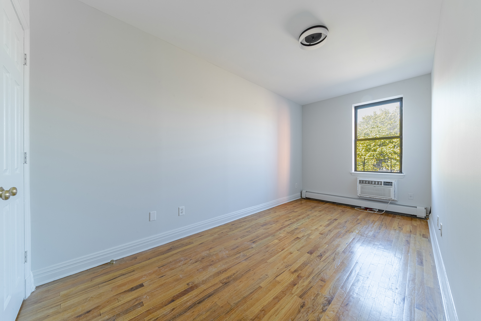 7 Mt Morris Park West, Unit D Manhattan, NY 10027 - Photo 12 of 16 an empty room with a window and wooden floor