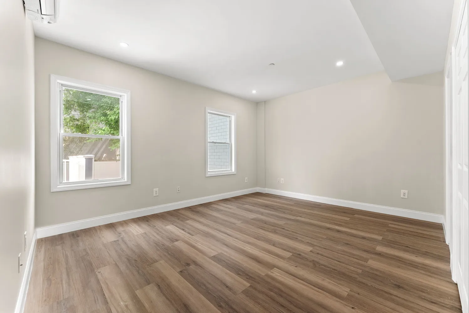 an empty room with wooden floor and windows