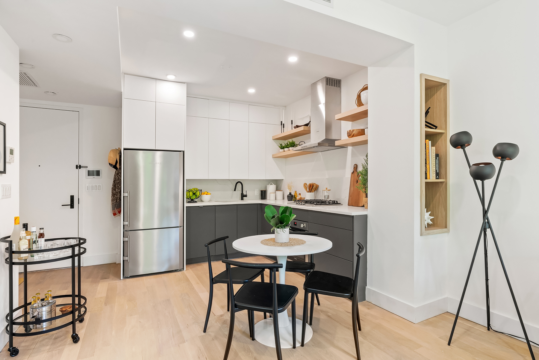 26 West 127th Street, Unit 4A Manhattan, NY 10027 - Photo 3 of 10 a kitchen with stainless steel appliances a refrigerator a stove a dining table and chairs with wooden floor