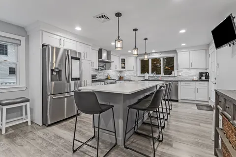 a kitchen with stainless steel appliances kitchen island granite countertop a dining table chairs sink and microwave